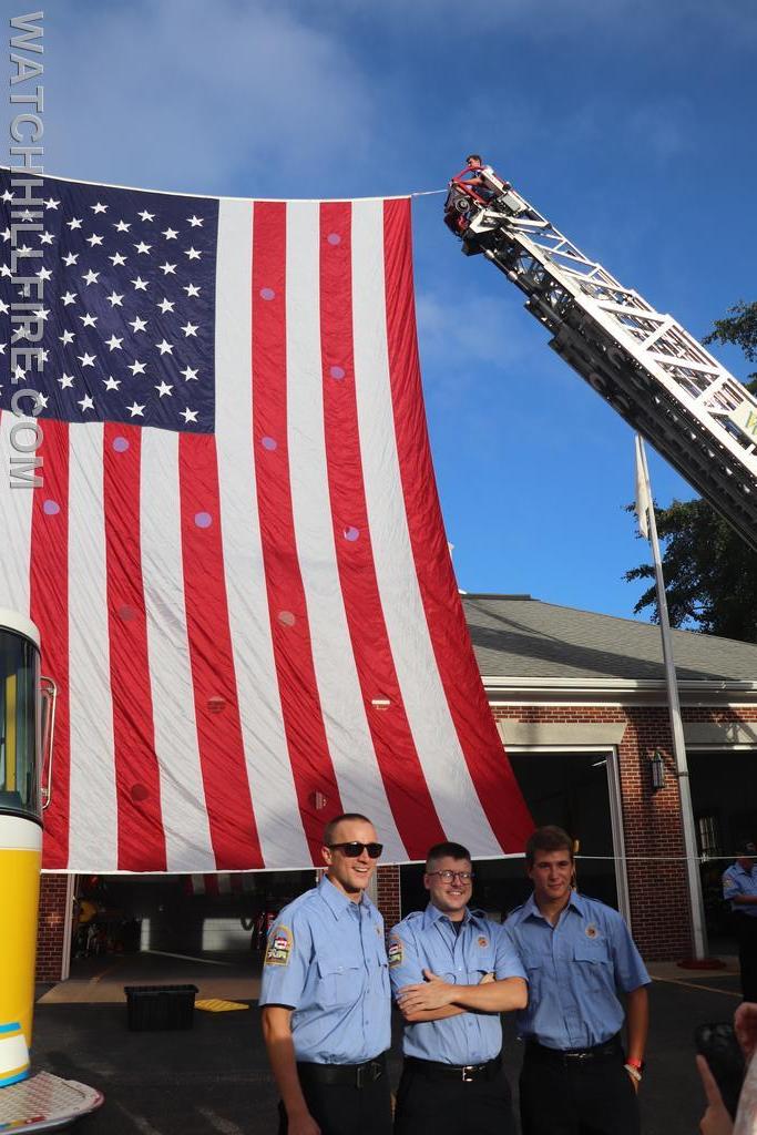 FF Majeika, Meyer, and Esposito in front of the ladder flag